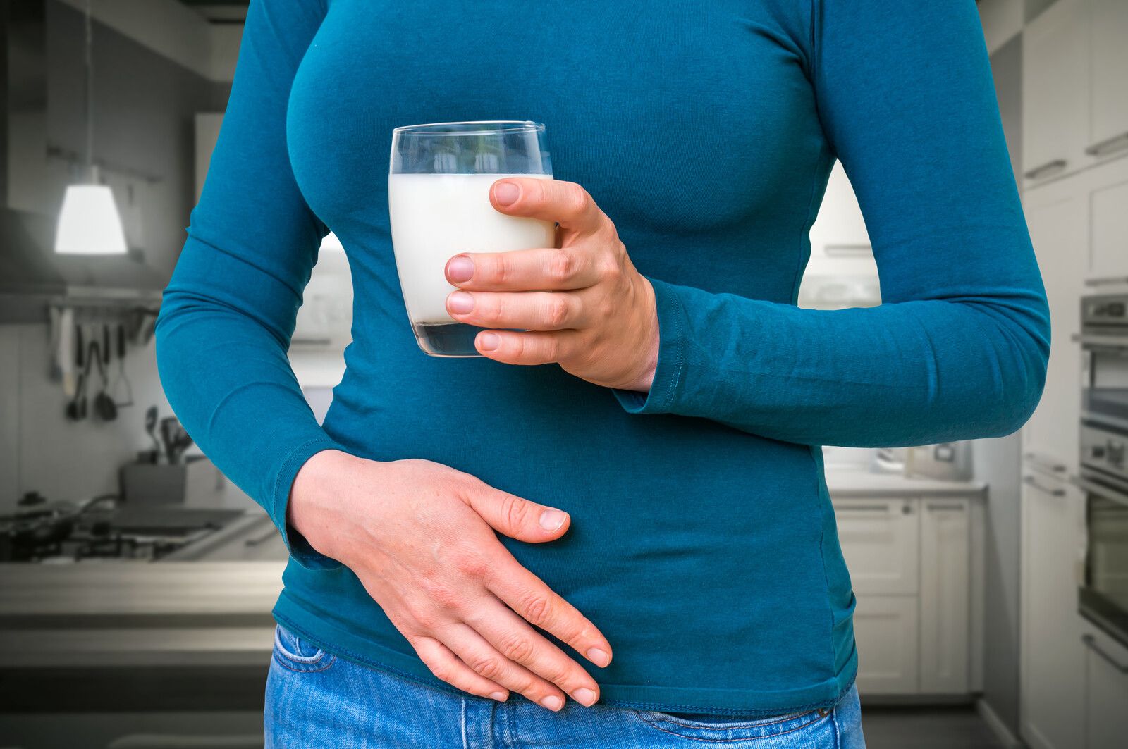 Alergie na mléko není intolerance laktózy - žena se sklenicí mléka a zažívacími problémy